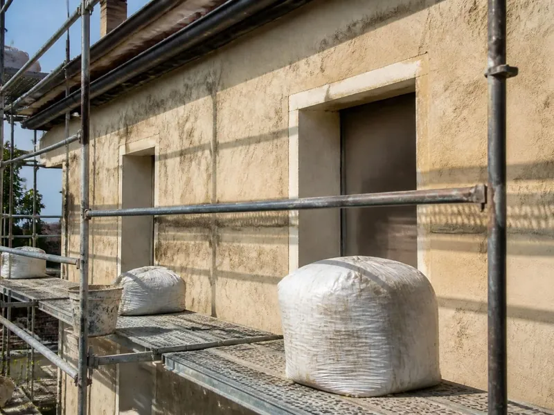 Échafaudage devant une façade enduite au plâtre en cours de ravalement à Dourdan